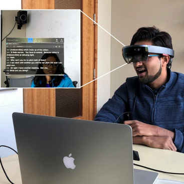 The first author (Dhruv Jain) wearing a HoloLens that shows real-time captions placed over a speaker in the group conversation using AR.